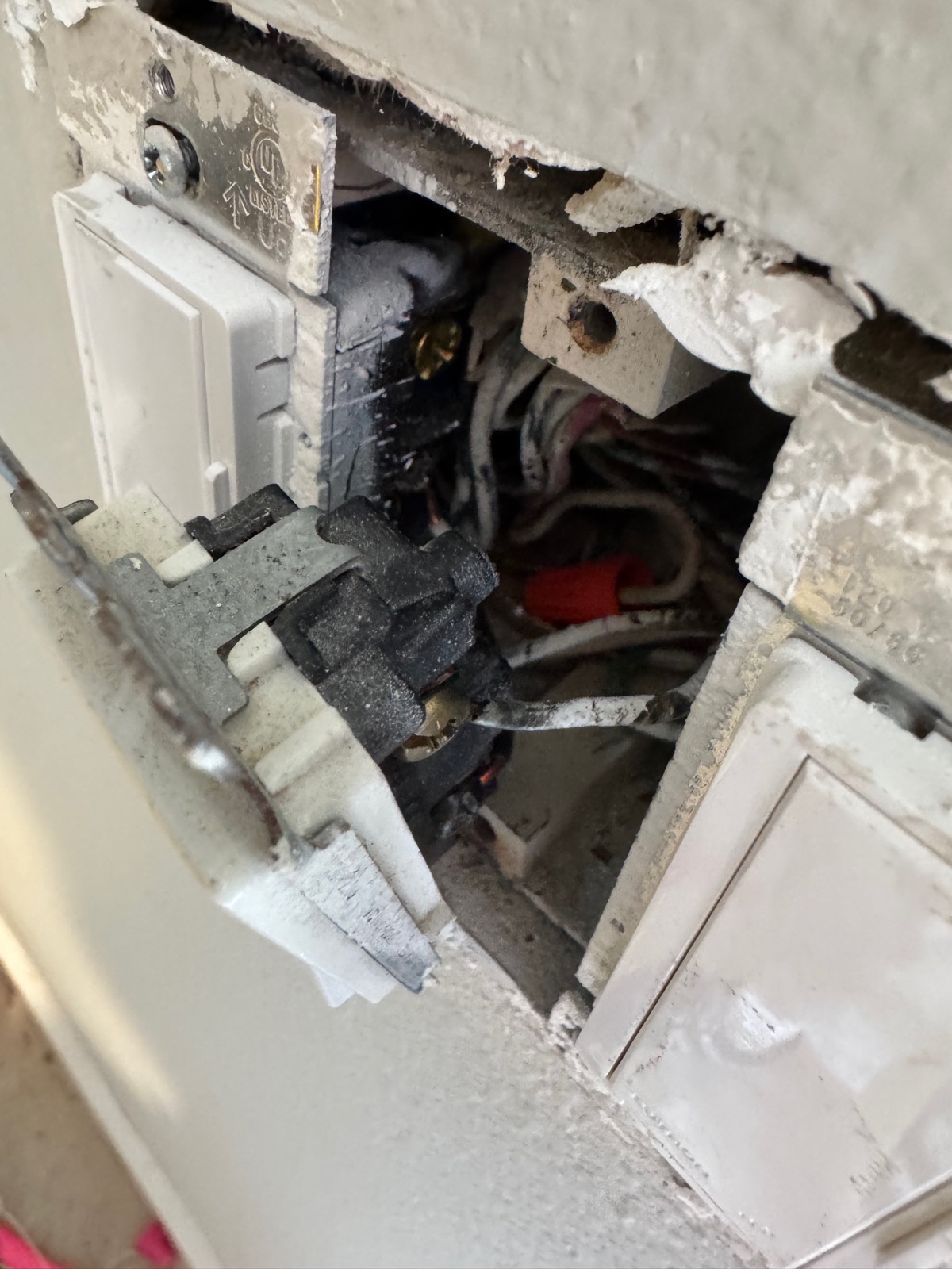 Multi-gang metal box with mechanical switch pulled forward; white conductors under red wire nut in the back