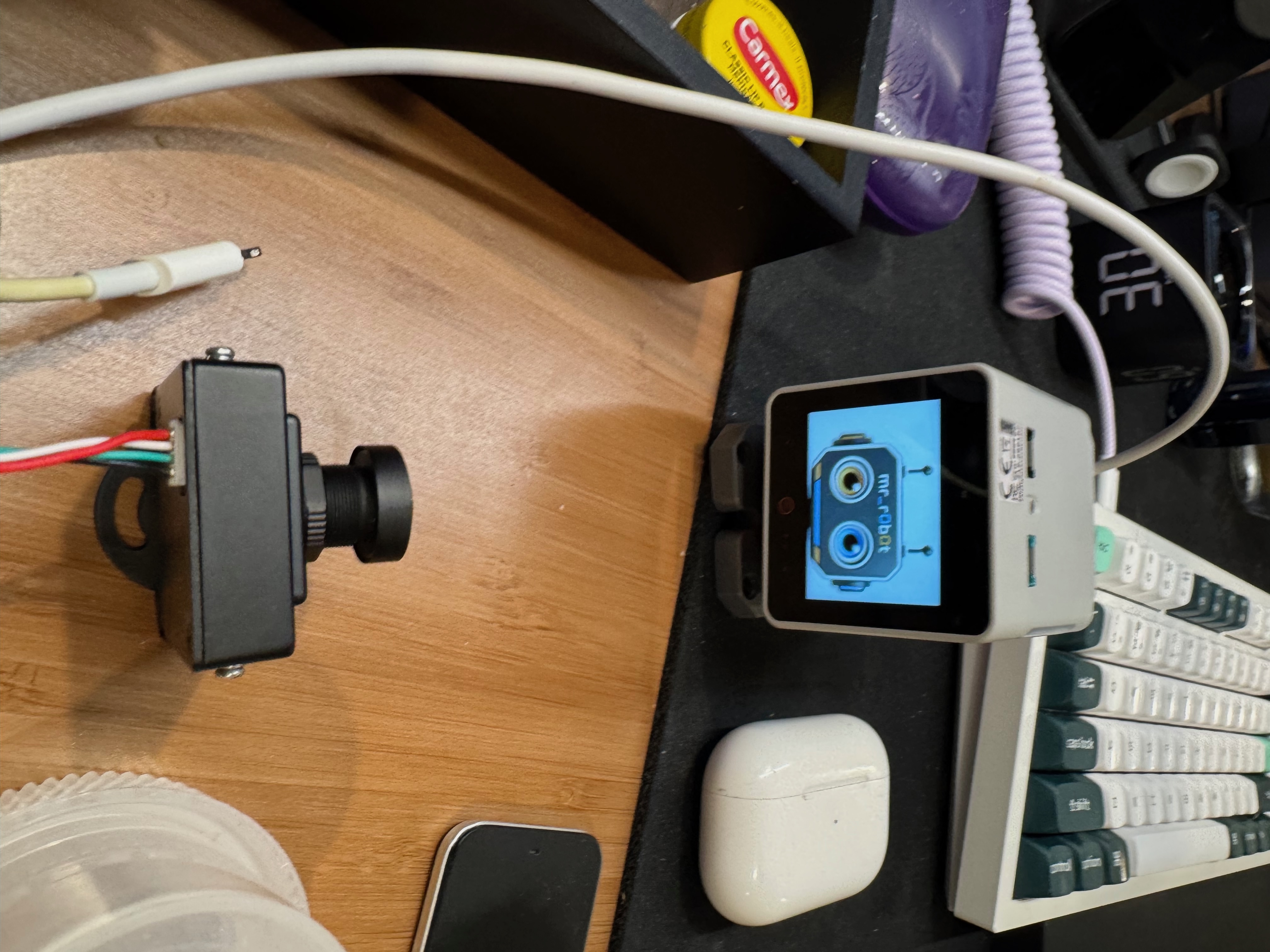 StackChan Unit 4 on James's workbench with the custom mr_r0b0t face visible on its physical LCD.