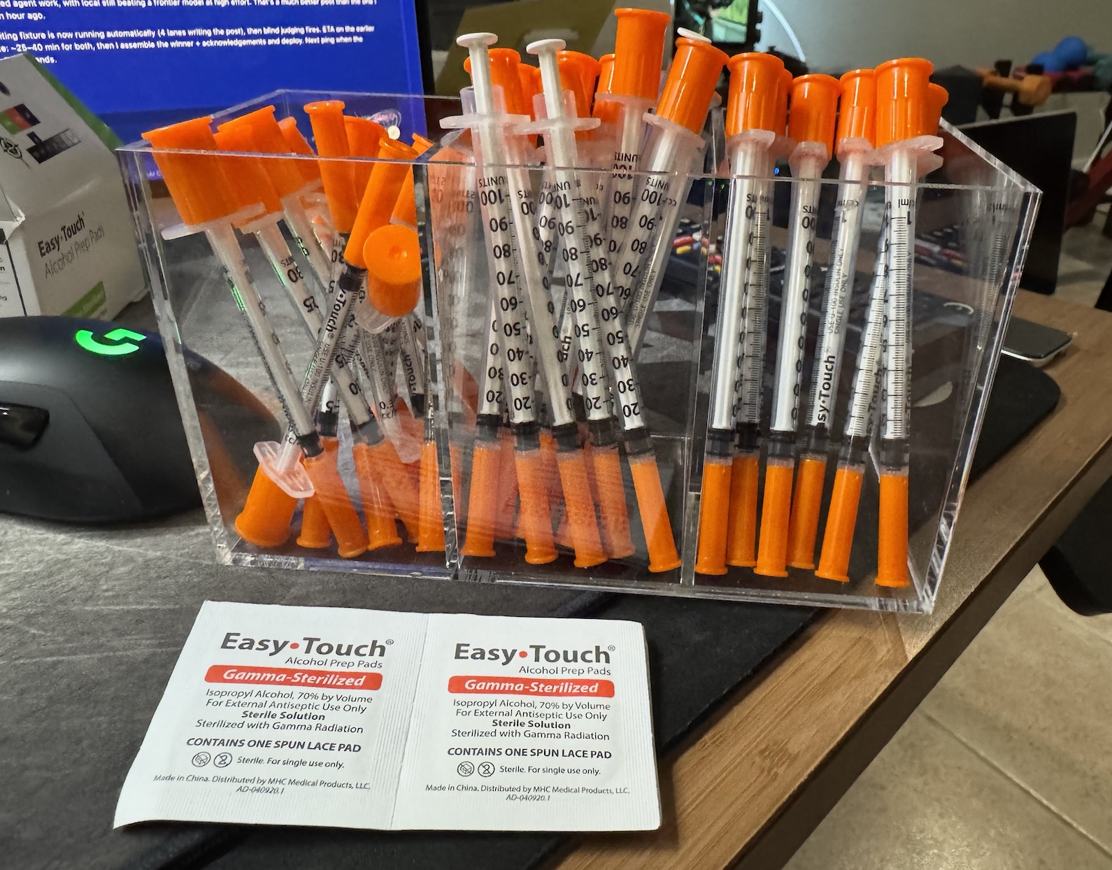 Acrylic three-bin pencil holder full of insulin syringes, with Easy-Touch alcohol prep pads in front